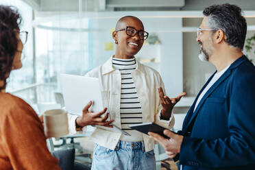 Group of professionals engaged in a lively discussion. Business woman exchanging ideas and communicating effectively with her colleagues. A vibrant and dynamic meeting in a startup office. - JLPSF31204