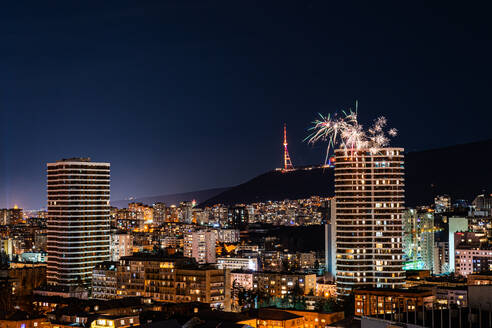 Ein farbenprächtiges Feuerwerk am Nachthimmel von Tiflis, das das Stadtbild in verschiedenen Farben und Mustern erhellt - ADSF52768