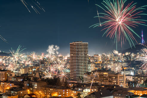 Der Nachthimmel über Tiflis wird von einem intensiven Feuerwerk erhellt, das die Stadtlandschaft unter sich in ein helles Licht taucht - ADSF52771