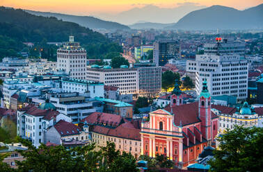 Luftaufnahme des Stadtbilds von Ljubljana bei Sonnenuntergang mit historischen Gebäuden mit roten Dächern und Bergen im Hintergrund - ADSF52773