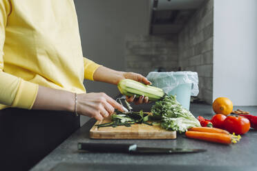 Woman peeling zucchini on kitchen counter at home - OLRF00155