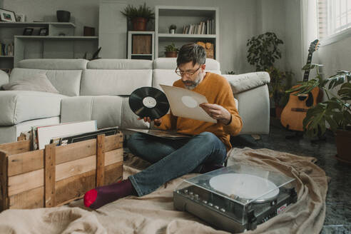 Man examining vinyl disc at home - DMGF01212