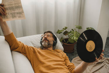 Mann, der zu Hause Musik hört und eine Schallplatte in der Hand hält - DMGF01227