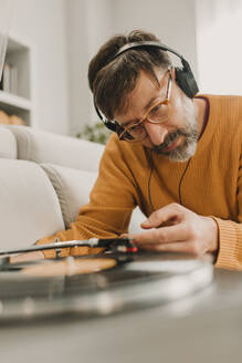 Mann hört Musik und stellt die Nadel auf einer Schallplatte ein - DMGF01237