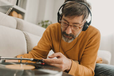 Mann hört Musik und stellt die Nadel einer altmodischen Schallplatte ein - DMGF01238
