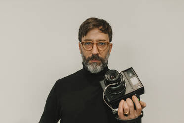 Man holding old instant camera against white background - DMGF01248