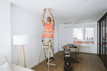 Handwerker, der auf einer Leiter steht und zu Hause arbeitet - EBBF08618