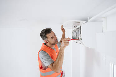 Älterer Techniker bei der Reparatur einer Klimaanlage zu Hause - EBBF08621
