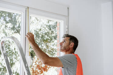 Älterer Techniker misst Fenster zu Hause - EBBF08628