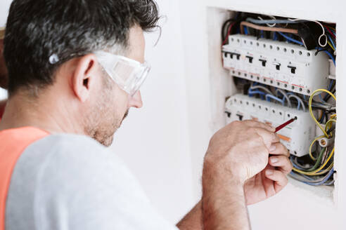 Maintenance engineer repairing fuse box at home - EBBF08639