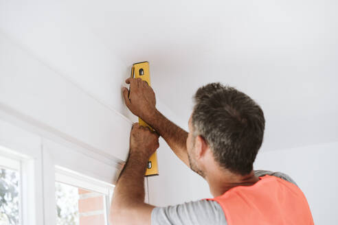 Handwerker mit Nivelliergerät in einem zu renovierenden Haus - EBBF08663