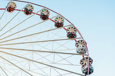 Von unten statisches Riesenrad vor einem klaren blauen Himmel, das seine Symmetrie und die bunten Muster auf den Fahrgastkabinen zur Geltung bringt - ADSF52843