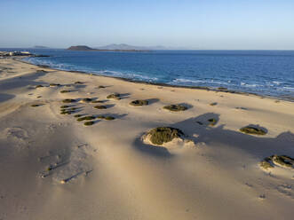 Das Licht der goldenen Stunde spült über den Sandstrand mit den Felsformationen in den Dünen von Corralejo, mit Blick auf das Meer auf Fuerteventura - ADSF52858