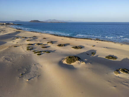 Das Licht der goldenen Stunde spült über den Sandstrand mit den Felsformationen in den Dünen von Corralejo, mit Blick auf das Meer auf Fuerteventura - ADSF52858