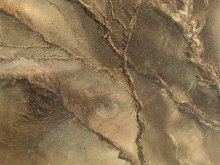 Luftaufnahme eines erdigen, strukturierten Geländes mit natürlichen Rissmustern, das an ein abstraktes Gemälde erinnert - ADSF52860