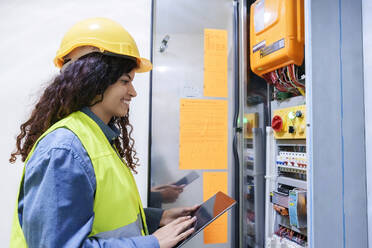 Smiling engineer holding tablet PC near server - AAZF01491