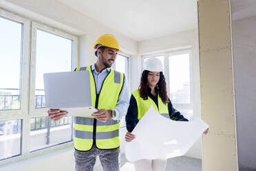 Architects discussing over blueprint at site - AAZF01501