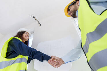 Junge Ingenieure beim Händeschütteln auf der Baustelle - AAZF01512