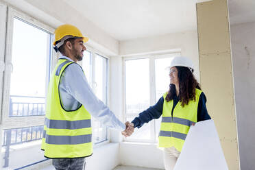 Lächelnde Architekten beim Händeschütteln auf der Baustelle - AAZF01513