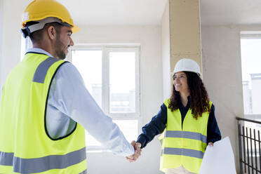 Lächelnder Architekt schüttelt einem Kollegen auf der Baustelle die Hand - AAZF01515