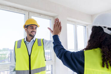 Architect giving high five to colleague at site - AAZF01524