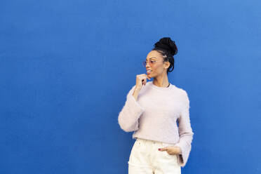Lächelnde Frau vor blauer Wand stehend - LMCF00887