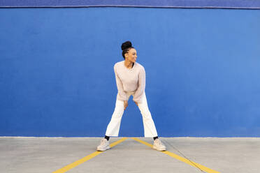 Happy young woman in front of blue wall - LMCF00894