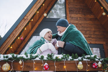 Glückliches Paar in eine Decke eingewickelt bei einer Blockhütte - OLRF00177