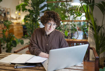 Botanikerin arbeitet am Laptop an einem Tisch im Pflanzengeschäft - VRAF00404