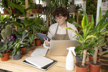 Botaniker mit Laptop und Tablet-PC am Tisch im Pflanzengeschäft - VRAF00440