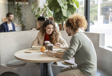 Happy businesswoman talking to colleague at office cafeteria - JCCMF11196