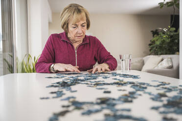 Ältere Frau spielt Puzzle zu Hause - UUF31156