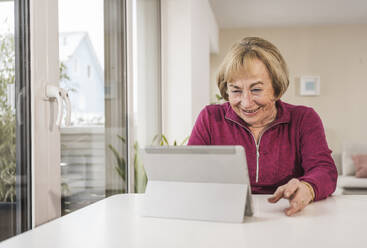 Happy senior woman using tablet PC at home - UUF31158