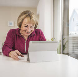 Smiling senior woman using tablet PC at home - UUF31159