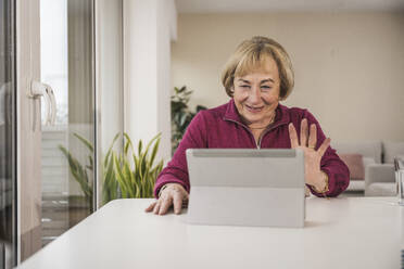 Smiling senior woman waving on video call through tablet PC - UUF31161