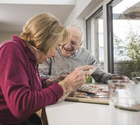 Glückliches älteres Paar betrachtet Fotos zu Hause - UUF31165