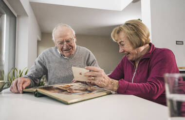 Happy senior man and woman looking at photographs - UUF31166