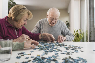Hauspflegerin spielt Puzzle-Spiel mit älterem Ehepaar - UUF31173