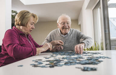 Glücklicher Mann und Frau spielen Puzzle-Spiel zu Hause - UUF31174