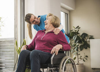 Happy home caregiver with senior woman sitting in wheelchair - UUF31184