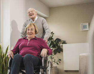 Glücklicher Mann mit Frau im Rollstuhl sitzend - UUF31188