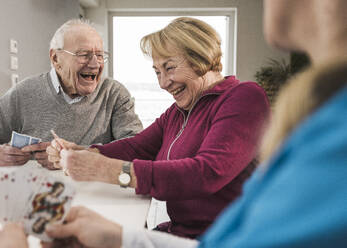 Happy senior couple playing cards at home - UUF31195