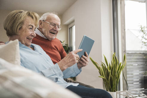 Glückliches Seniorenpaar bei der Nutzung eines Tablet-PCs zu Hause - UUF31208