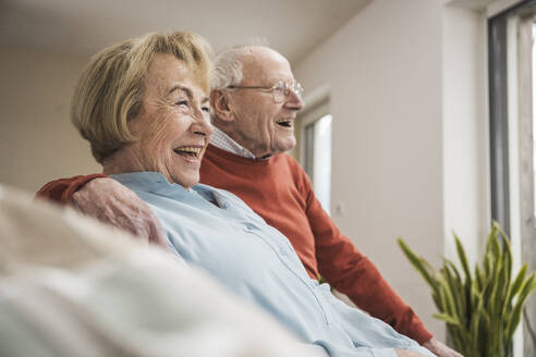 Happy senior couple sitting in living room at home - UUF31214