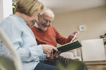 Happy senior woman and man looking at photographs - UUF31215