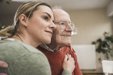 Smiling home caregiver consoling and embracing senior man - UUF31221