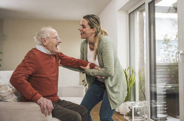 Home caregiver taking care of senior man in living room - UUF31227