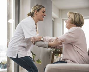 Happy nurse taking care of woman at home - UUF31235