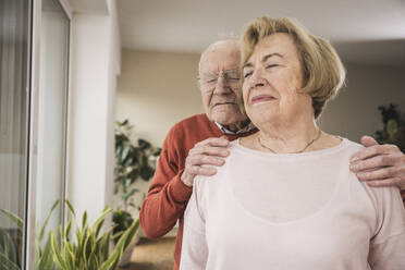 Smiling senior man and woman with eyes closed at home - UUF31251