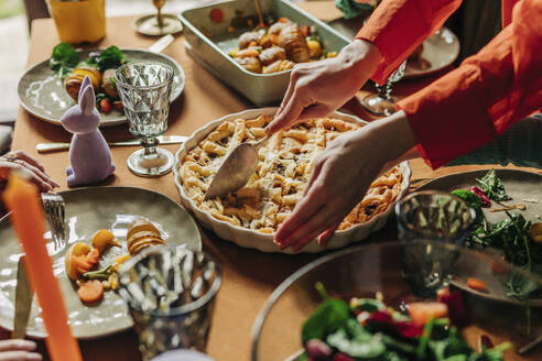 Hands of woman cutting savory pie on dining table at Easter dinner - VSNF01648